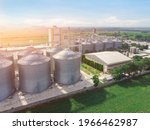 Aerial view of drone,Agricultural Silos - Building Exterior, Storage and drying of grains, wheat, corn, soy, sunflower against the golden sky with rice fields.