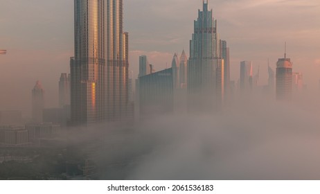 Aerial View Of Dubai City Early Morning During Fog Timelapse. Sunrise At Futuristic City Skyline With Skyscrapers And Towers From Above. Sun Reflected From Glass Surface