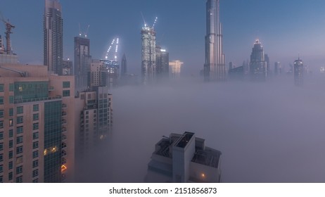 Aerial View Of Dubai City Early Morning During Fog Night To Day Timelapse. Futuristic City Skyline With Skyscrapers And Towers Under Construction From Above