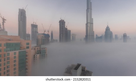 Aerial View Of Dubai City Early Morning During Fog Night To Day Timelapse. Futuristic City Skyline With Skyscrapers And Towers Under Construction From Above