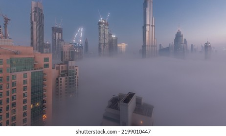 Aerial View Of Dubai City Early Morning During Fog Night To Day Timelapse. Futuristic City Skyline With Skyscrapers And Towers Under Construction From Above