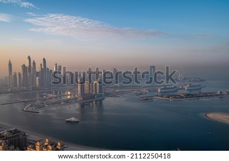 Aerial view of Dubai Marina captured during sunrise from the palm islands. The tree-shaped Palm Jumeirah island is known for glitzy hotels, posh apartment towers and upmarket global restaurants.