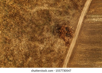 Aerial View Of Dusty Dirt Road Through Grassy Plain Landscape, Top View From Drone Pov