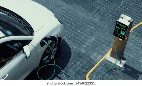 Aerial view electric car recharging battery from EV charging station at city center public car park. Future innovative rechargeable EV car using alternative clean and sustainable energy. Peruse - Powered by Shutterstock