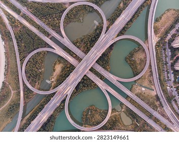 Aerial view of elevated ring roads and circular interchanges crossing turquoise rivers in Wuhan, China, showcasing modern urban infrastructure and traffic patterns.