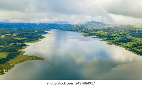Aerial view of Embalse de Tominé in Guatavita, Cundinamarca. Showcasing serene water, lush greenery, and cloudy skies