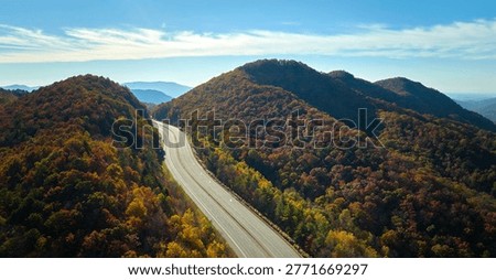 Aerial view of empty I-40 freeway in North Carolina leading to Asheville through Appalachian mountains in golden fall season. Interstate transportation concept