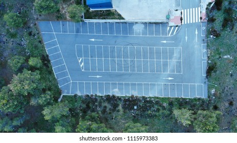 Aerial View Of An Empty Parking, Dirty And With Tire Marks, Surrounded By Large Trees