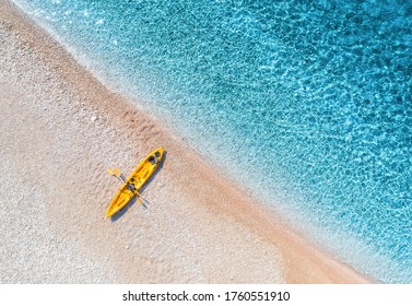 Aerial view of empty sandy beach with yellow canoe, sea coast with transparent blue water in sunny bright day in summer. Travel in Croatia. Top view of boat. Landscape with kayak at sunset. Travel - Powered by Shutterstock