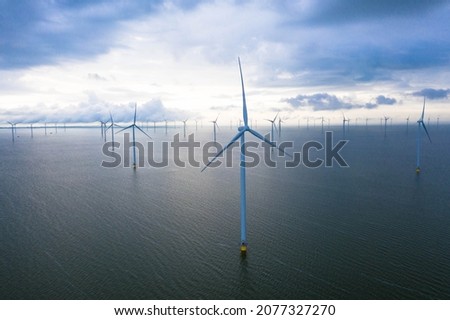 Aerial view of enormous windmills stand in the sea along a dutch sea. Fryslân wind farm, the largest inland wind farm in the world. Friesland, Afsluitdiijk, Ijsselmeer, Breezanddijk, Netherlands