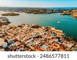 Aerial view of Es Castell traditional town on the Menorca coast with harbor and boats at sunset during summer tourist season. Picturesque balearic town close to Mahon seen from drone