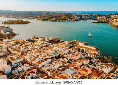 Aerial view of Es Castell traditional town on the Menorca coast with harbor and boats at sunset during summer tourist season. Picturesque balearic town close to Mahon seen from drone - Powered by Shutterstock