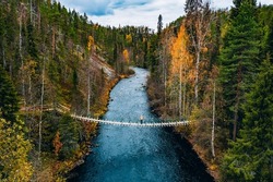Aerial View Of Fall Forest And Blue River With Bridge In Finland. Beautiful Autumn Landscape.