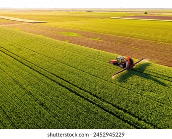 Aerial view of a farmer driving a tractor on a rural path between vibrant wheat green crops - Powered by Shutterstock