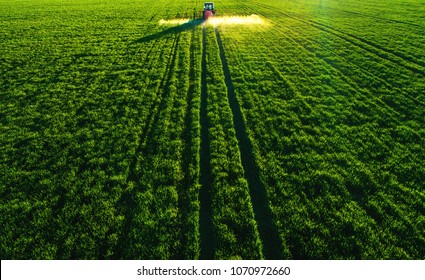 Aerial view of farming tractor plowing and spraying on field. - Shutterstock ID 1070972660