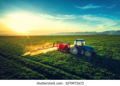 Aerial view of farming tractor plowing and spraying on field. - Shutterstock ID 1070972672