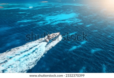 Aerial view of fast floating yacht on blue sea at sunny day in summer. Travel in Sardinia, Italy. Aerial view of speed boat, sea lagoon, transparent azure water. Top drone view. Tropical seascape