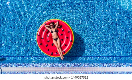 Aerial View Of Female In Bikini Lying On A Floating Mattress In Swimming Pool, Inflatable Mattress Watermelon Toy In Swimming Pool Water From Above, Summer Vacation Concept Background