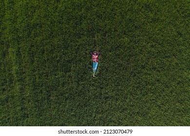 Aerial View Of Female Farmer Laying In Green Wheat Field And Resting, Top Down Drone Pov Of Woman Agronomist In Wheatgrass