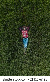 Aerial View Of Female Farmer Laying In Green Wheat Field And Resting, Top Down Drone Pov Of Woman Agronomist In Wheatgrass