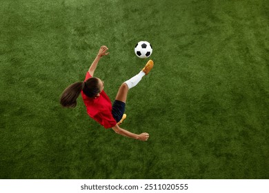 Aerial view of female football athlete kicking ball in mid air on green lush stadium during training session. Concept of women and sport, team games, movement, victory, action. Ad - Powered by Shutterstock