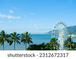 An aerial view of the ferris wheel, treetops, lagoon and hilly backdrop of Cairns Esplanade — Coral Sea, Cairns; Far North Queensland, Australia