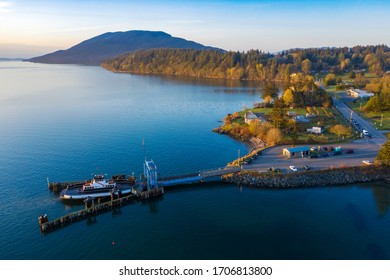 Aerial View Of A Ferry Boat Landing At The Island Dock. Aerial Shot Of A Small 21 Car Ferry Landing At The Lummi Island Ferry Dock On A Beautiful Sunlit Morning In The The Pacific Northwest, USA.