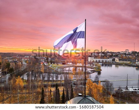 Aerial view of Finnish flag on the tower of Town Hall against the red sunrise sky in Joensuu, Finland.