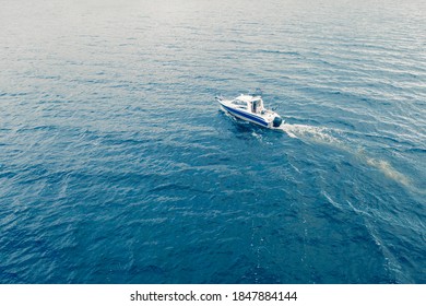 Aerial view fisherman on boat at the ocean. Top view beautiful seascape with the fishing boat. Aerial view fishing motor boat with angler. Ocean sea water wave reflections. Motor boat in the ocean. - Powered by Shutterstock