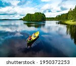 Aerial view of fishing boat with young woman and man in blue summer lake in Finland