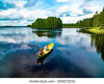 Aerial view of fishing boat with young woman and man in blue summer lake in Finland