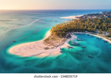 Aerial view of the fishing boats on tropical sea coast with sandy beach at sunset. Summer holiday on Indian Ocean, Zanzibar, Africa. Landscape with boat, green trees, transparent blue water. Top view - Shutterstock ID 1348035719