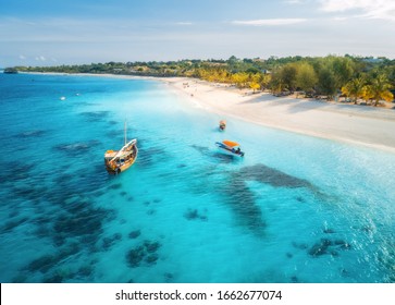 Aerial View Of The Fishing Boats On Tropical Sea Coast With Sandy Beach At Sunset. Summer Holiday In Zanzibar, Africa. Landscape With Boat, Yacht In Clear Blue Water, Green Palm Trees. View From Above