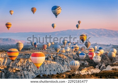 Aerial view of a fleet of hot air balloons, in Cappadocia, Turkey, at sunrise. Cappadocia is a popular tourist destination.
