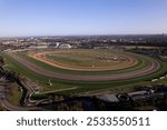 Aerial view of Flemington Racecourse in Melbourne, Australia, showcasing the entire racetrack and surrounding cityscape under a clear blue sky.