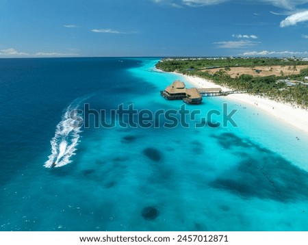 Aerial view of floating boats, bungalow, boat in ocean at sunset in summer. Restaurant on the sea. Top view of yachts, azure water, white sandy beach, palm trees. Luxury resort in Kendwa, Zanzibar