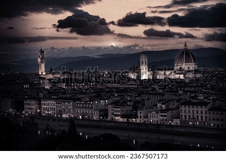 An aerial view of Florence at night with the cathedral towering over other buildings, illuminated by the bright lights
