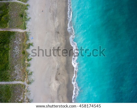 Aerial view of Florida tropical ocean waters meeting the sandy beach trails.