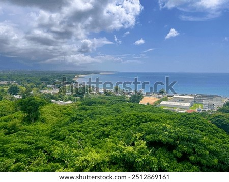 Aerial view of fluffy cloudy, dramatic sky, buildings, Caribbean jungle and coastline