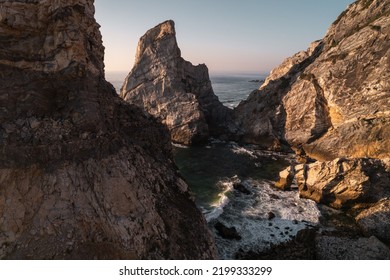 Aerial View Of Foamy Sea Waves Crushing Near Rough Cliffs Of Ursa Beach At Sunrise In Portugal