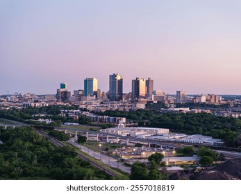 Aerial view of Fort Worth, Texas at dusk, vibrant cityscape, prominent skyscrapers, modern low residential buildings, active rail yard, and lush greenery - Powered by Shutterstock