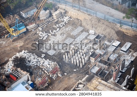 Aerial view of foundation work at construction site with piles, concrete bases, cranes, and excavation pit. Suitable for engineering, infrastructure, development, and building concepts