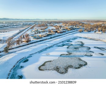 Aerial View Of Freezen Pond With Waterfowl And  Industrial Area Of Fort Collins, Colorado With A Waste Water Treatment Plant, Winter Scenery At Sunset