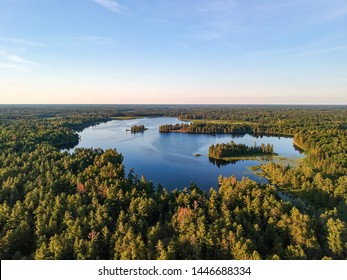 Aerial View Of Fresh Water Lake Surrounded By Coniferous Forests Going To Horizon, Sunny Summer Day. Northern Ontario, Canada. Shot From The Air With Drone At Sunset Hour.