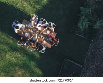 Aerial View Of Friends Toasting Drinks At Outdoor Party In Restaurant. Group Of People Sitting Around A Table In Garden And Having Drinks..