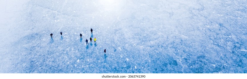 Aerial view of frozen lake with many ice skaters on the ice. Beautiful winter sunny day outdoor. Background concept. 