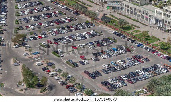Aerial view full cars at large outdoor parking\
lots timelapse in Dubai, UAE. Office and recidential parking\
congestion and crowded parking lot with other cars try getting in\
and out, finding parking