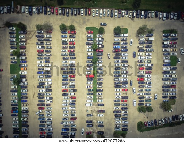 Aerial view full cars at large outdoor parking\
lots in Houston, Texas, USA. Outlet mall parking congestion and\
crowded parking lot, other cars try in and out, finding parking\
space. Vintage filter