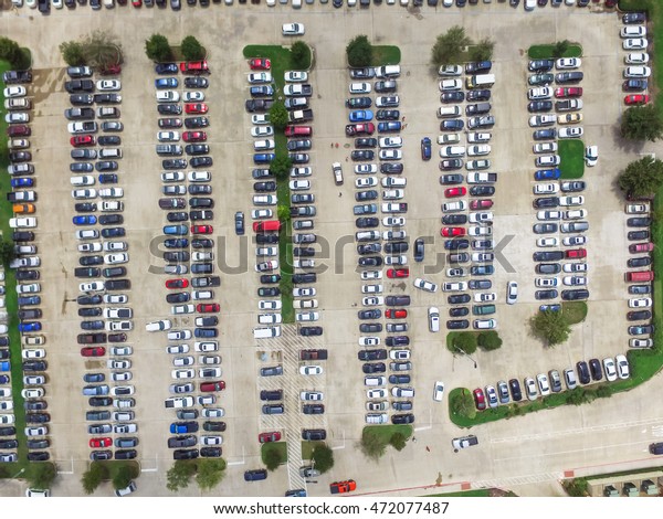 Aerial view full cars at large outdoor parking\
lots in Houston, Texas, USA. Outlet mall parking congestion and\
crowded parking lot with other cars try getting in and out, finding\
parking space.