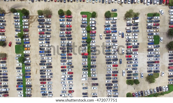 Aerial view full cars at large outdoor parking\
lots in Houston, Texas, USA. Outlet mall parking congestion and\
crowded parking lot, other cars try getting in and out, finding\
parking space. Panorama